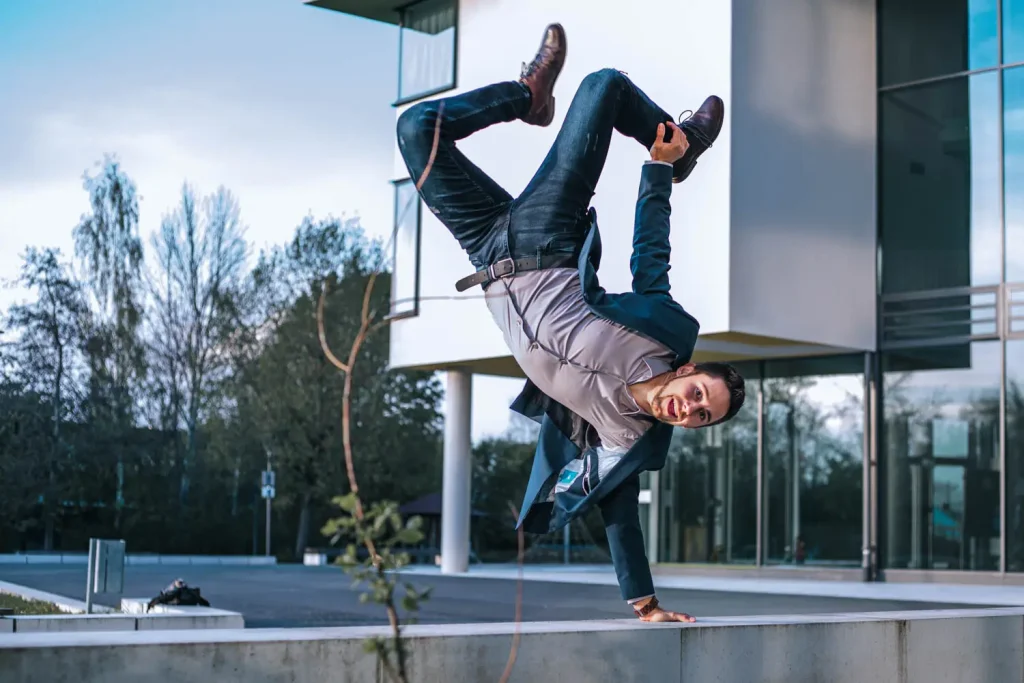 Mann im Anzug macht einen Handstand mit nur einer Hand